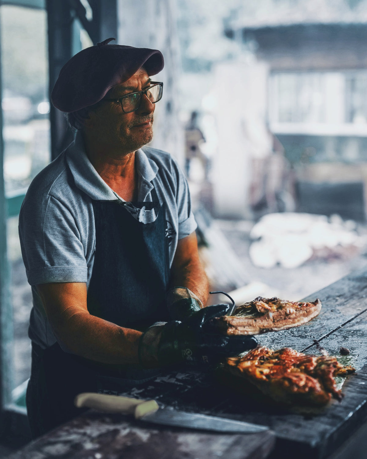 Retrato de asador con boina y delantal junto a la parrilla, mirando el fuego