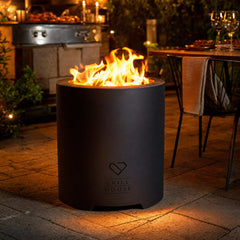 Brasero Ranco encendido en una terraza de noche, con la mesa puesta al lado