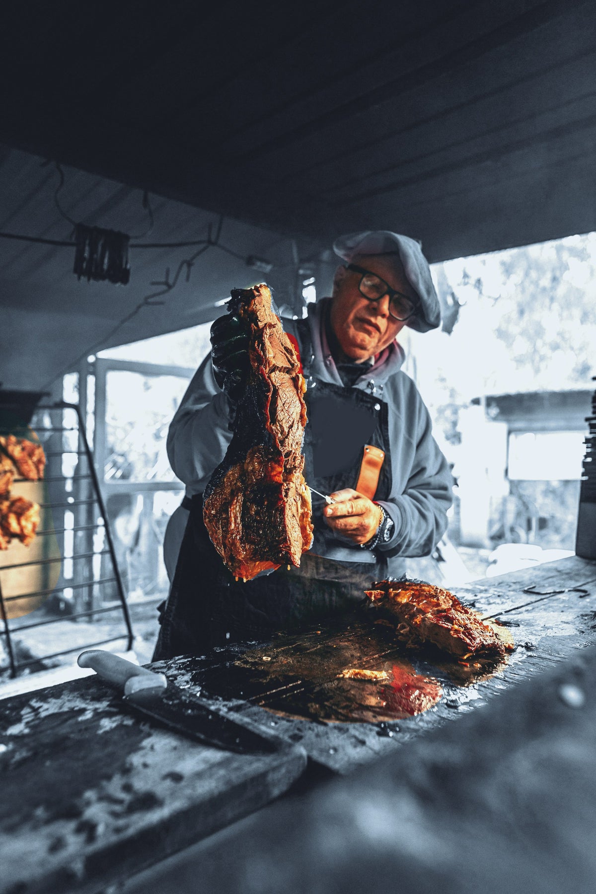 Asador levantando un costillar recién sacado de la parrilla, sobre la mesa de trabajo